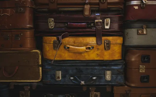 Vintage suitcases stacked in a rustic setting, showcasing classic travel charm.