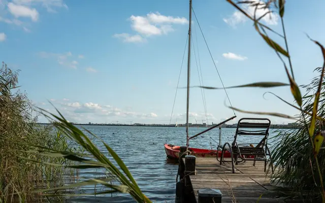 Serene lake view featuring a docked sailboat and chair, perfect for relaxation and reflection.