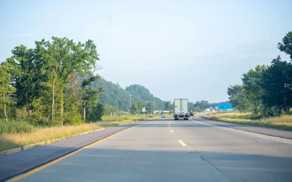 Tranquil highway scene with truck driving in Minnesota's lush summer landscape.